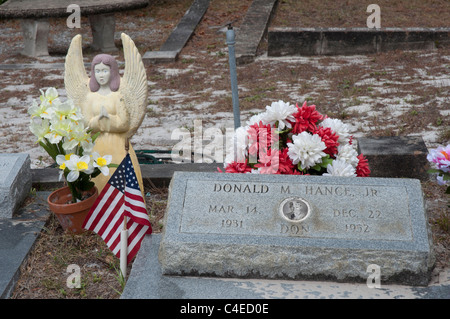 Fiori artificiali e bandiera americana contrassegnare il gravesites nel cimitero di Carrabelle lungo la costa del Golfo della Florida. Foto Stock