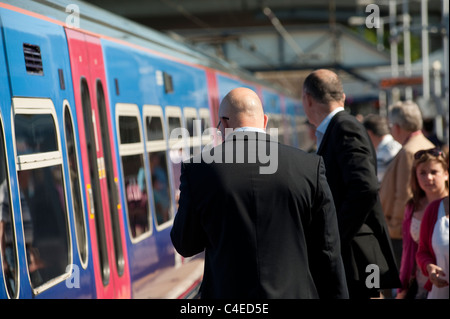 Passeggeri in piedi su una stazione ferroviaria in attesa della piattaforma a bordo di una prima capitale collegare il treno in Inghilterra. Foto Stock