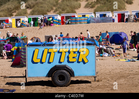 La folla e la plastica raccolta di lettiera carro rimorchio su la bandiera blu di sabbia costiera spiagge a Woolacombe Bay Beach, Devon, Regno Unito Foto Stock