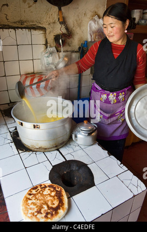 Il rendering di latte di yak per rendere il burro nel tè-house Sade, un villaggio tibetano a nord di Julong, Sichuan, in Cina. Foto Stock