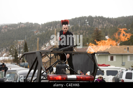 Un uomo vestito come un punk rocker sorge in cima a un funebre con una accesa una fiamma thrower presso i morti congelati Guy Festival Foto Stock