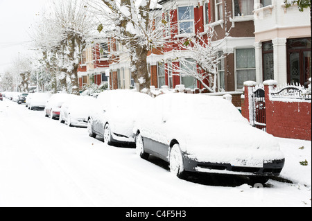 Coperta di neve auto in strada residenziale, London, Regno Unito Foto Stock