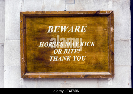 Attenzione, i cavalli possono cacciare o il morso di un cartello di segnalazione fuori la sfilata delle Guardie a Cavallo su Whitehall, London, Regno Unito Foto Stock
