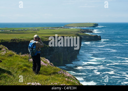 dh Scottish Seacliffs estate BIRSAY ORKNEY Birdwatcher guardando bird watcher Uccelli uomo scogliera bordo binocolo costa Regno Unito scozia Foto Stock