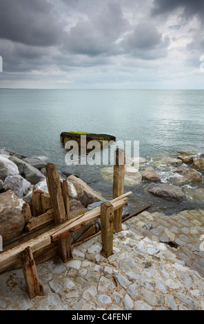 Bawdsey sulla costa di Suffolk su un moody pomeriggio estivo che mostra entrambe le vecchie e nuove difese del mare Foto Stock