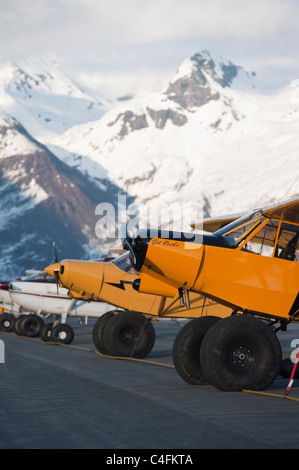 Due giallo Piper Super Cubs parcheggiata di fronte alle montagne su asfalto al 2010 giorno di maggio Fly-in, Valdez, Alaska Foto Stock