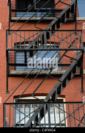 Close up di metallo fire escape attaccato ad un vecchio edificio di mattoni rossi. Foto Stock