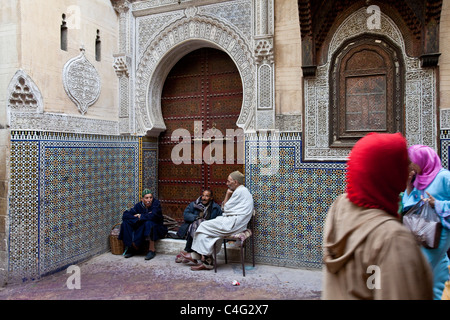 Gli uomini seduti fuori moschea Sidi Ahmed Tijani, la Medina di Fez, Marocco Foto Stock