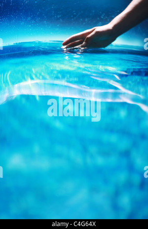 La mano in acqua blu Foto Stock