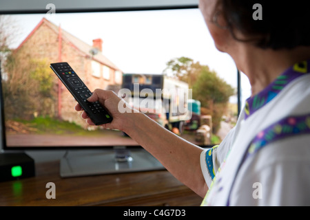 Donna con telecomando puntando al TV Foto Stock