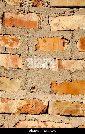 Frammento di vecchio quadrato di mattoni rossi con il muro di cemento di molti su di esso. Foto Stock