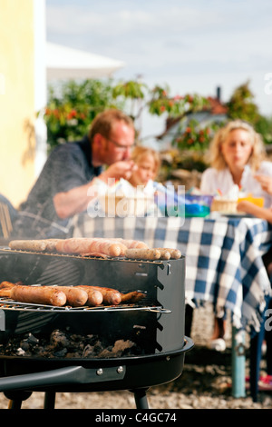 Famiglia avente un barbecue in giardino - focus sulla cucina in primo piano Foto Stock