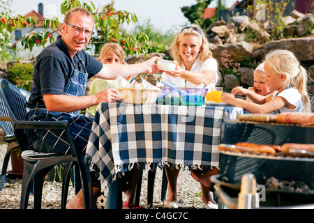 Famiglia avente un barbecue in giardino, mangiare Foto Stock