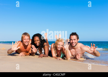 Il gruppo di quattro amici - uomini e donne - sulla spiaggia avente un sacco di divertimento nella loro vacanza Foto Stock