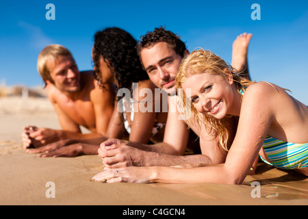 Il gruppo di quattro amici - uomini e donne - sulla spiaggia avente un sacco di divertimento nella loro vacanza Foto Stock