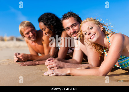 Il gruppo di quattro amici - uomini e donne - sulla spiaggia avente un sacco di divertimento nella loro vacanza Foto Stock