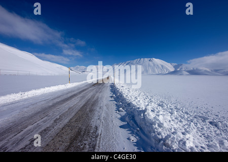 La strada che attraversa il Piano Grande in inverno, Parco Nazionale dei Monti Sibillini, Umbria, Italia Foto Stock