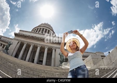 I giovani adulti donna bionda di scattare una foto con una fotocamera digitale a l'Avana, Cuba. Sagoma orizzontale, vita, angolo basso Foto Stock