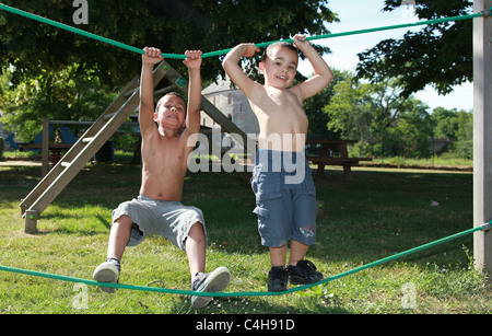 Due giovani ragazzi che giocano sulla palestra apparecchiatura nel parco. Foto Stock