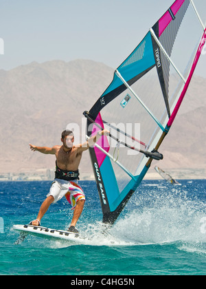 Un windsurf eseguendo acrobazie sul mar rosso presso il resort di Eilat in Israele. Foto Stock