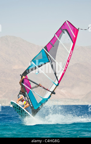 Un windsurf eseguendo acrobazie sul mar rosso presso il resort di Eilat in Israele. Foto Stock