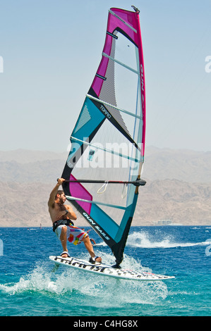 Un windsurf eseguendo acrobazie sul mar rosso presso il resort di Eilat in Israele. Foto Stock