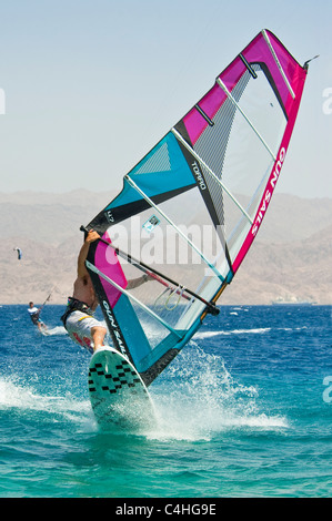 Un windsurf eseguendo acrobazie sul mar rosso presso il resort di Eilat in Israele. Foto Stock