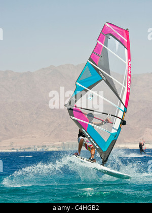 Un windsurf eseguendo acrobazie sul mar rosso presso il resort di Eilat in Israele. Foto Stock