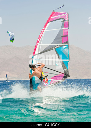 Un windsurf eseguendo acrobazie sul mar rosso presso il resort di Eilat in Israele. Foto Stock