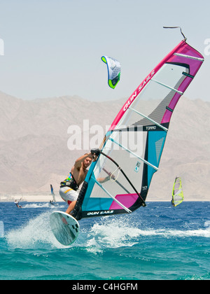 Un windsurf eseguendo acrobazie sul mar rosso presso il resort di Eilat in Israele. Foto Stock