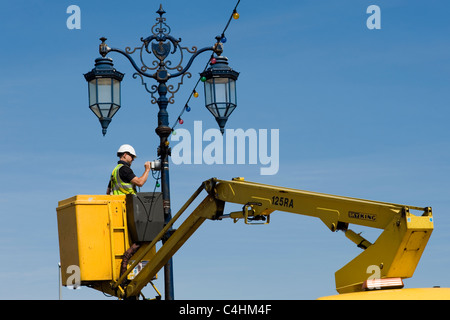 Workman esecuzione di interventi di manutenzione su un lungomare standard della lampada Foto Stock