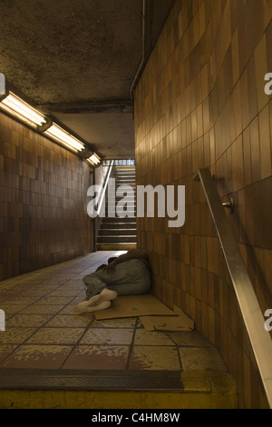 Senzatetto uomo dorme in metropolitana e ingresso/uscita, Rockefeller Center di New York City. Foto Stock