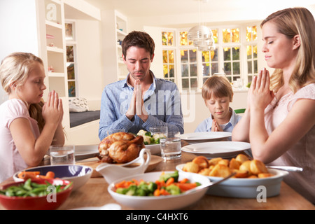 Famiglia dicendo la preghiera prima di mangiare Arrosto Foto Stock