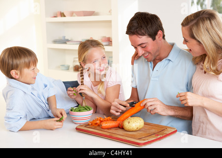 La famiglia felice la pelatura verdure in cucina Foto Stock