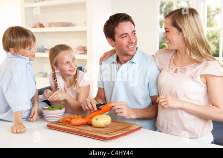 La famiglia felice la pelatura verdure in cucina Foto Stock