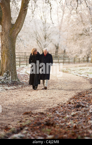 Coppia senior in inverno a piedi attraverso il pupazzo di neve il paesaggio Foto Stock