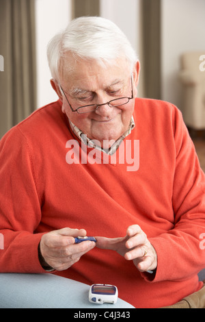 Uomo Senior Controllo livello di zucchero nel sangue a casa Foto Stock