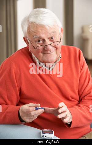 Uomo Senior Controllo livello di zucchero nel sangue a casa Foto Stock