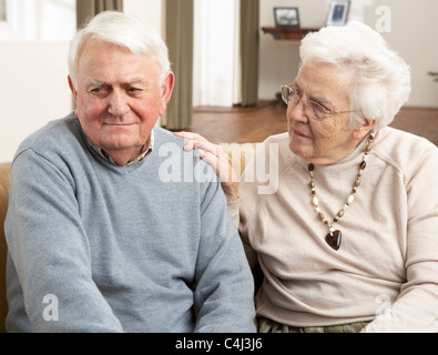 Senior donna consolante marito a casa Foto Stock