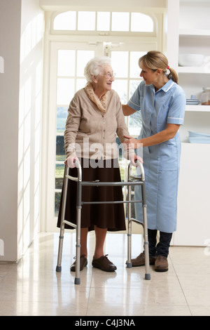 Accompagnatore aiutare anziani donna Senior con telaio a piedi Foto Stock