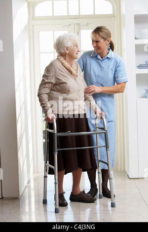 Accompagnatore aiutare anziani donna Senior con telaio a piedi Foto Stock