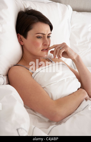 Preoccupato donna recante sveglio a letto Foto Stock