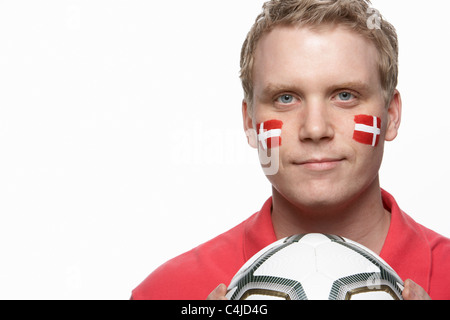Giovane Maschio appassionato di calcio con bandiera danese dipinto sul volto Foto Stock