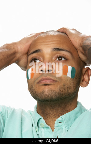 Deluso maschi giovani appassionati di sport con la bandiera della Costa d'Avorio dipinto sul volto Foto Stock