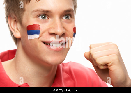 Giovane Maschio appassionato di calcio con bandiera serba dipinto sul volto Foto Stock