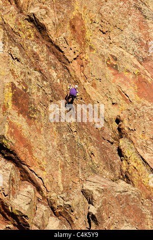 Eldorado Springs, CO - un rocciatore in viola abseils una scogliera in ritiro dalla sua salita in Eldorado Canyon State Park. Foto Stock