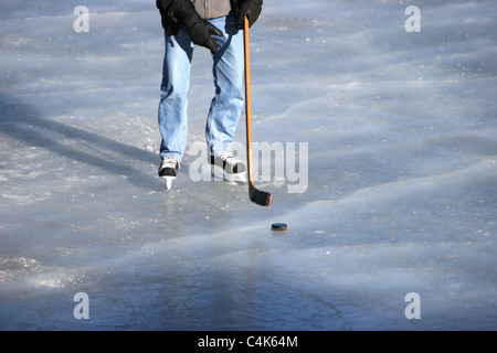 Evergreen, Colorado - un giocatore di hockey pattini sul ghiaccio durante il tentativo di manipolare il puck nell'obiettivo. Foto Stock