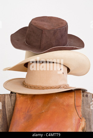 Cappelli Western alta impilati con chaps sul vecchio recinto in legno Foto Stock