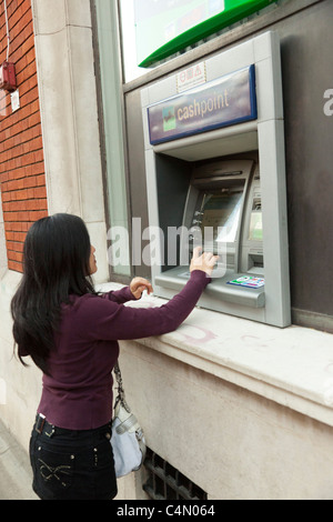 Giovane donna tramite bancomat / BANCOMAT Foto Stock