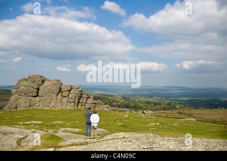 Orizzontale di un ampio angolo di visione di un giovane godendo la vista su tutta Haytor Rocks sul Parco Nazionale di Dartmoor su un giorno d'estate. Foto Stock